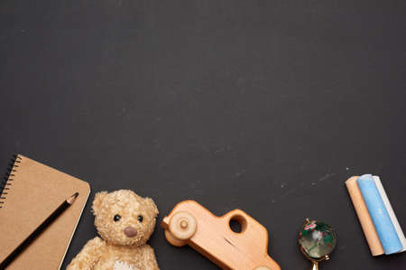 brown teddy bear, wooden toy car and glass globe on black chalk board, back to school, copy space