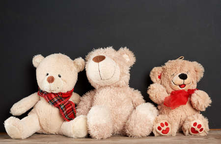 brown teddy bear sits on a brown wooden table, behind an empty black chalk board, place for an inscription, back to schoolの写真素材
