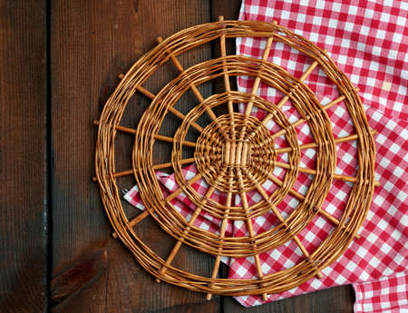 round wicker stand for pots on a brown wooden table, top view