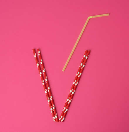 paper multicolored cocktail tubes on pink background, flat lay