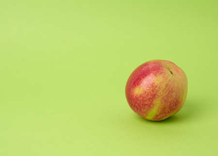 ripe red round apple on a green background, autumn harvest, close up, copy spaceの写真素材