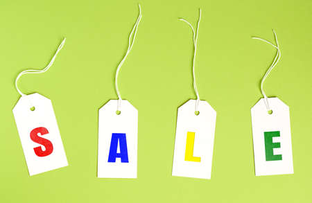 white paper tags with inscription sale on a green background, seasonal discount concept, top viewの写真素材