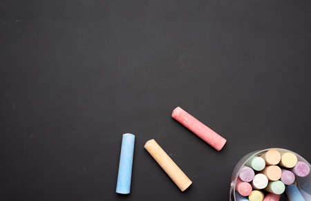 multicolored chalk in a plastic bucket on a black background, top view