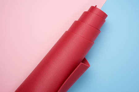 twisted red neoprene mat for yoga and sports on pink blue background
