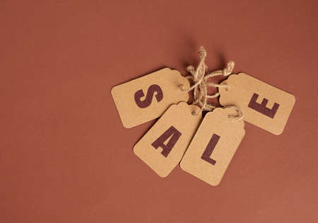 brown paper tags with inscription sale on brown background, seasonal discount concept, top viewの写真素材