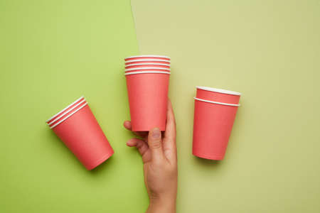 stack of red paper disposable cups on a green background, concept eco-friendly, zero waste