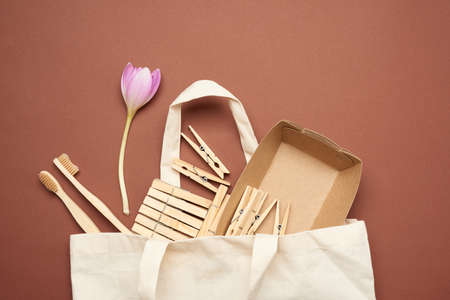 wooden clothespins and toothbrushes, paper plates in white textile reusable bag on brown background, top view, zero wasteの写真素材