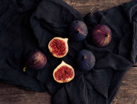 ripe whole and halved purple figs on a black napkin, top viewの写真素材