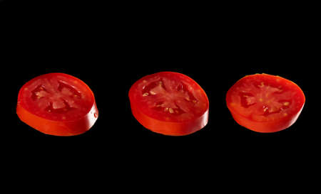 three slices of red ripe tomato isolated on black background, close up