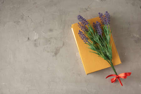 closed yellow book, lavender branch on gray cement background, top view, copy spaceの写真素材