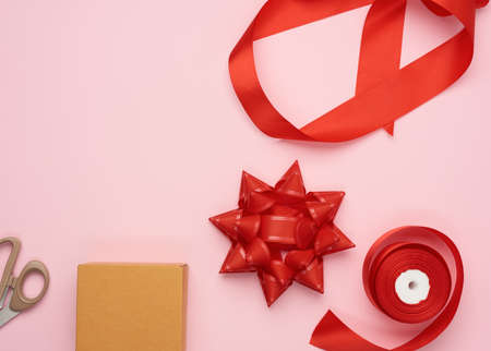 brown box and red silk ribbon with bow, items for gift wrapping, top view