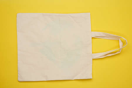 empty beige textile bag on yellow background, rejection of plastic bags, flat lay, zero wasteの写真素材