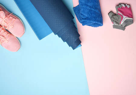 rolled up sports mat, pink sneakers, towel and gloves for sports, copy space