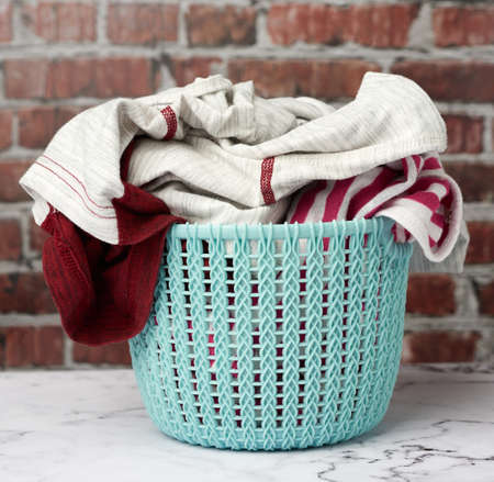 laundry basket and folded laundry, brown brick wall background, close upの写真素材