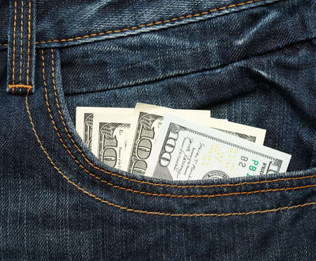 paper hundred United States dollar bills in the pocket of jeans, close up