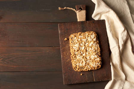baked rectangular crumble cake with fruit filling on wooden board, brown background, top view, copy...