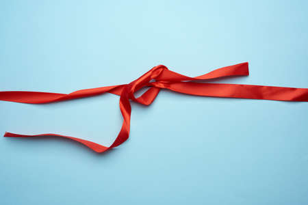 curled red silk ribbon on blue background, top viewの写真素材