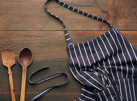 blue textile kitchen apron with white stripes and wooden spoons, top viewの写真素材