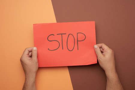 two male hands hold a red sheet with the inscription stop, top viewの写真素材
