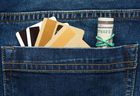 rolled paper american dollars and plastic bank card with magnetic stripe in the back pocket of blue jeans, close upの写真素材
