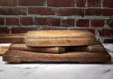very old vintage rectangular kitchen cutting board against brown brick wall backgroundの写真素材