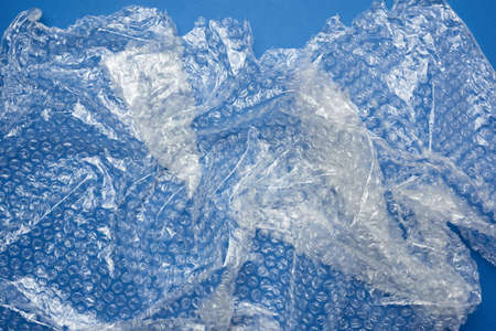 crumpled piece of polyethylene with air bubbles on a blue wooden background, packing material