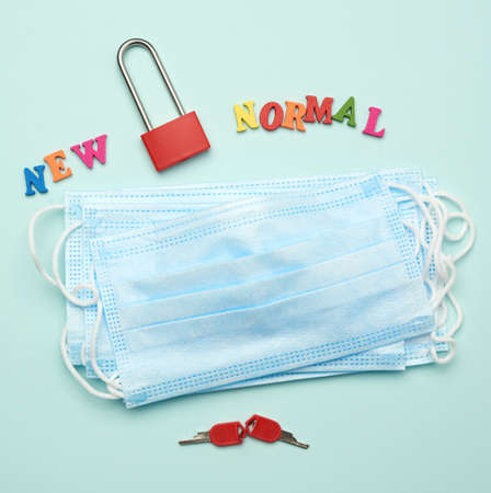 stack of disposable masks and a metal lock on a blue background, daily life during quarantine and...