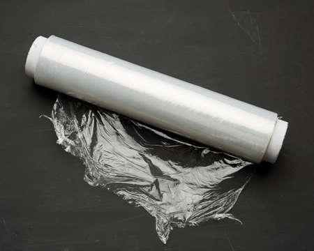 roll of wound white transparent film for wrapping food, black background, close up