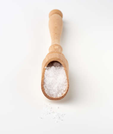 large crystals of white sea salt in a brown wooden spoon, top viewの写真素材