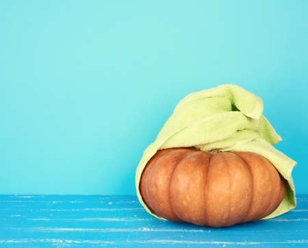 round orange pumpkin wrapped in a green terry towel, concept of relaxation, spa and beauty treatmentsの写真素材
