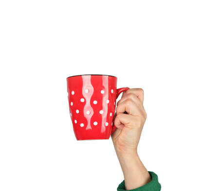 red ceramic cup in a female hand on a white background, hand is raised up