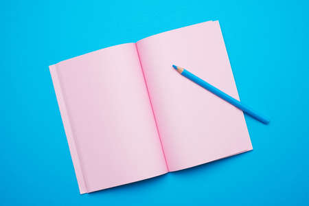 open notepad with empty pink sheets on a blue background, top view