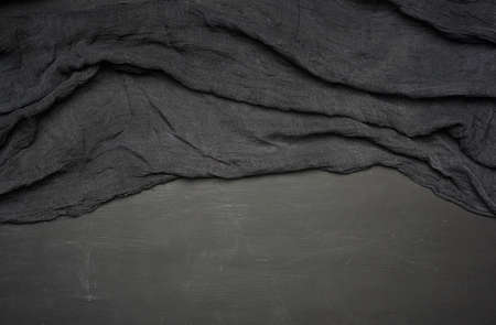 black kitchen textile towel folded on a black wooden table, top view, empty space