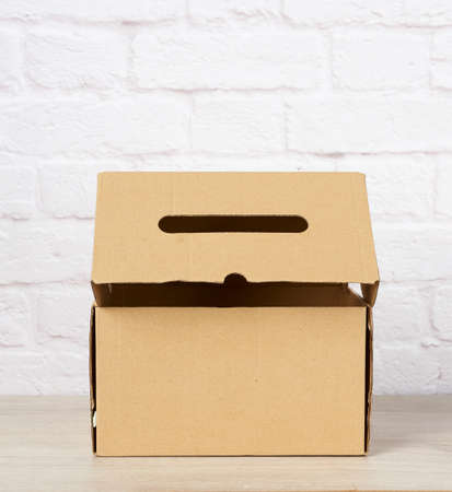 rectangular box made of brown corrugated cardboard on a white brick wall background, close up