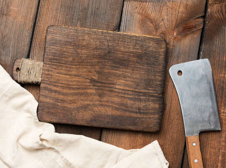 empty cutting board and large kitchen knife for cutting meat and vegetables on a brown wooden...