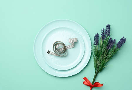 round ceramic plate and centimeter on green background, slimming concept, top viewの写真素材