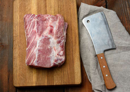 knife and raw pork tenderloin on a wooden cutting board, top viewの写真素材