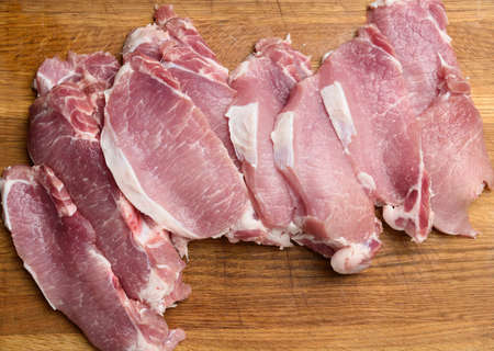 sliced pork tenderloin on a wooden cutting board, top viewの写真素材
