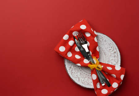 white round ceramic plates, fork with knife on a red background, top view. Table setting, copy spaceの写真素材