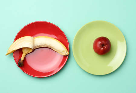 red ripe apple and banana lie in a round ceramic plate, top view, healthy foodの写真素材