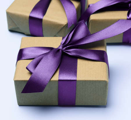 box wrapped in brown paper and tied with a purple silk ribbon with a bow, gift on a blue background, top view,の写真素材