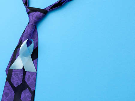 silk purple mens tie and blue ribbon folded in a loop on blue background, symbol of the fight and...