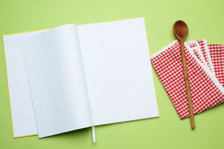 open notebook with blank white sheets and wooden spoon on green background, top viewの写真素材