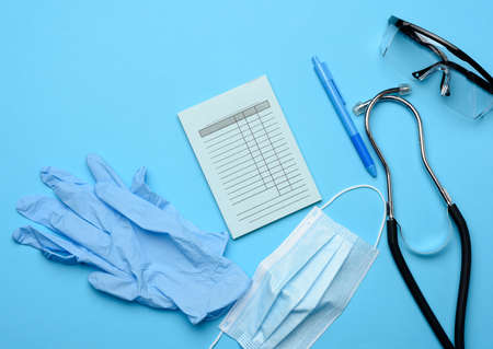 disposable medical mask and latex gloves, next to paper template for prescription, blue background, top viewの写真素材