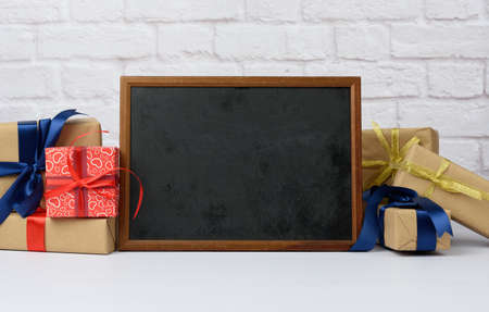 empty wood frame and stack of various gift boxes on white brick background, festive backdropの写真素材