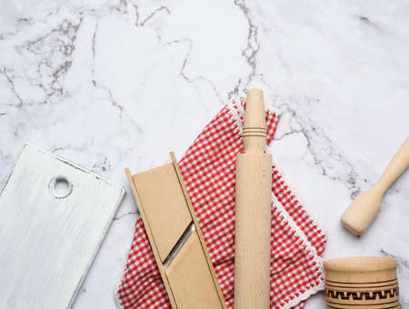 wooden kitchen utensils on white marble table, top view
