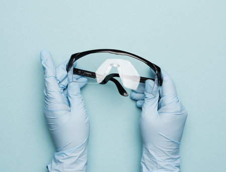 hand hold protective plastic glasses on a blue background, close upの写真素材