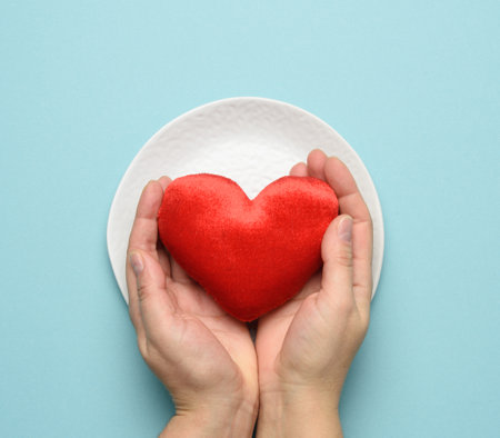 red heart lies in a white ceramic plate on a blue background, top viewの写真素材