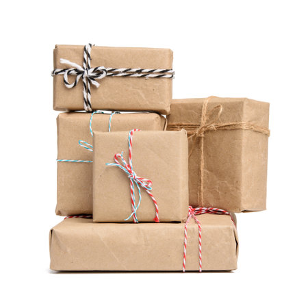 big stack of gifts wrapped in brown kraft paper and tied with rope, boxes isolated on white...