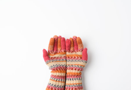 two female joined palms in knitted multi-colored mittens on a white background, top viewの写真素材